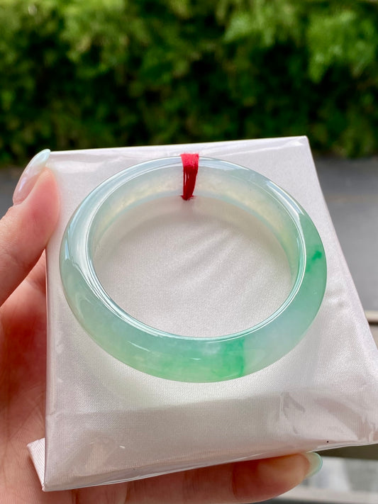 Light green translucent jadeite bangle in a gift box, circular inner opening visible