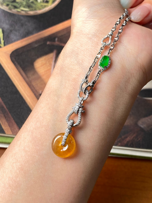 Silver-tone link necklace with green oval pendant and golden-yellow donut charm