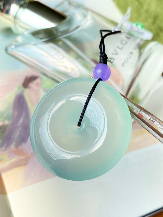 Mint green jade disc pendant with black cord and small purple bead top