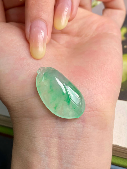 Light green jadeite melon pendant in palm, glossy teardrop shape with small loop