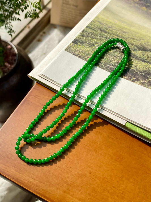 Green jadeite beaded necklace with layered strands and small silver clasp