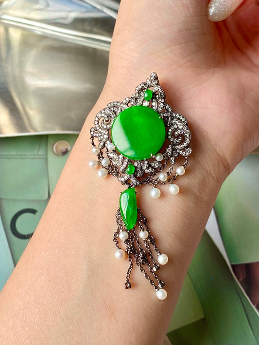 Round green jadeite brooch with ornate silver setting, dangling pearl drops