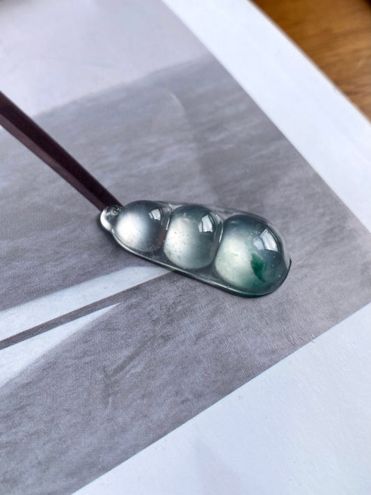 Green-flecked jadeite bean pendant in silver bezel, angled close-up