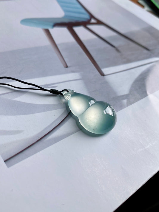 Light green jadeite gourd pendant on black cord, stone shaped like a droplet