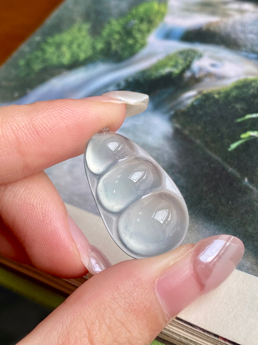 Jadeite bean pendant held in hand; translucent milky white teardrop shape, unset