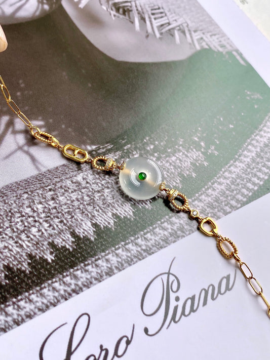 Gold safety-disc bracelet with white jade bead and green center detail
