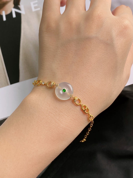 Gold safety-disc bracelet on wrist with white disc bead and green center