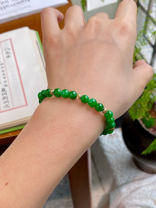 Green jadeite beaded bracelet on wrist with gold spacers and red center