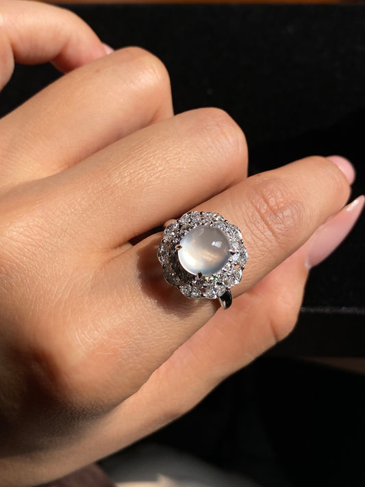 Icy white jadeite cabochon ring with halo of clear stones