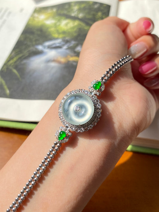 Icy white donut bracelet on hand: silver chain, blue center, green charm accents