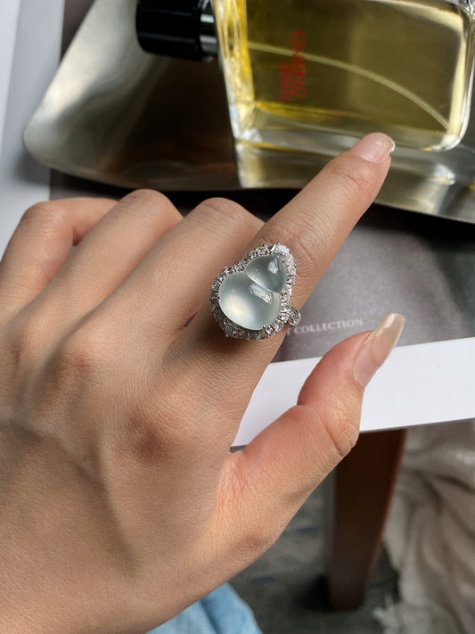 Silver-tone ring with oval light jade center and sparkling halo stones