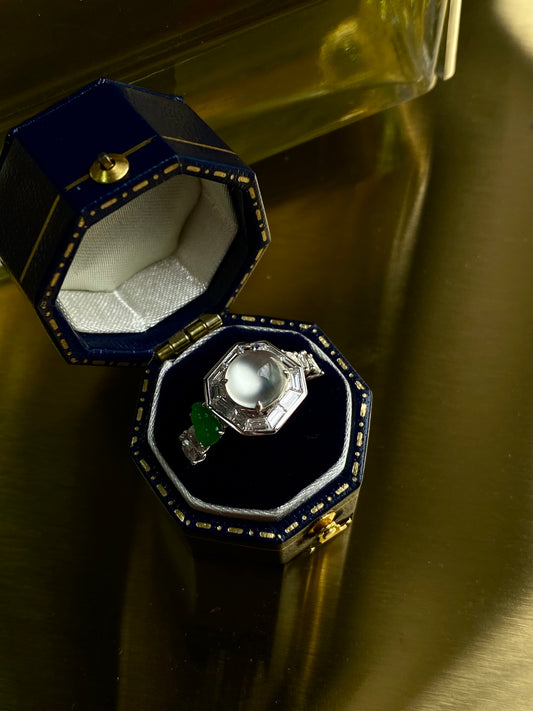 Octagonal bezel cabochon ring with green accents, displayed in blue-lined box
