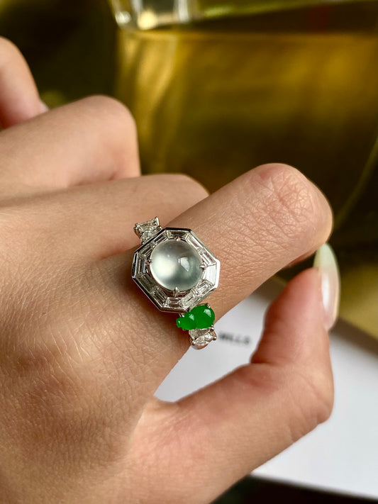 Silver cabochon ring with white stone and small green gemstone, on open palm
