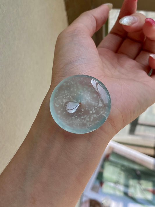 Round jadeite safety disc with frosted speckled pattern and glossy surface in hand.