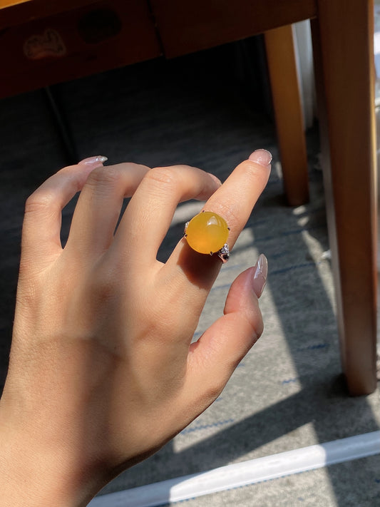 Jadeite cabochon ring on hand featuring golden yellow oval stone in dark blue frame