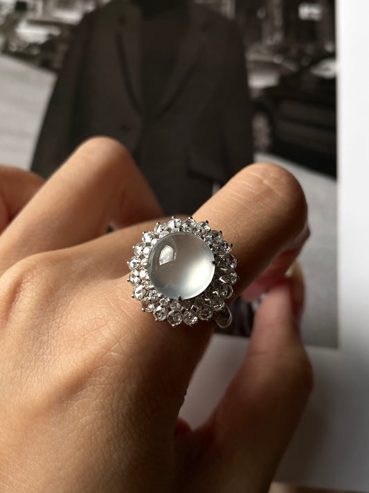 White jadeite cabochon ring with clear stone halo and silver-toned band