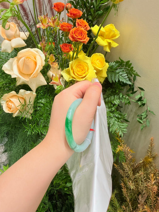 Slim light green jade bangle on hand, smooth round glossy bracelet