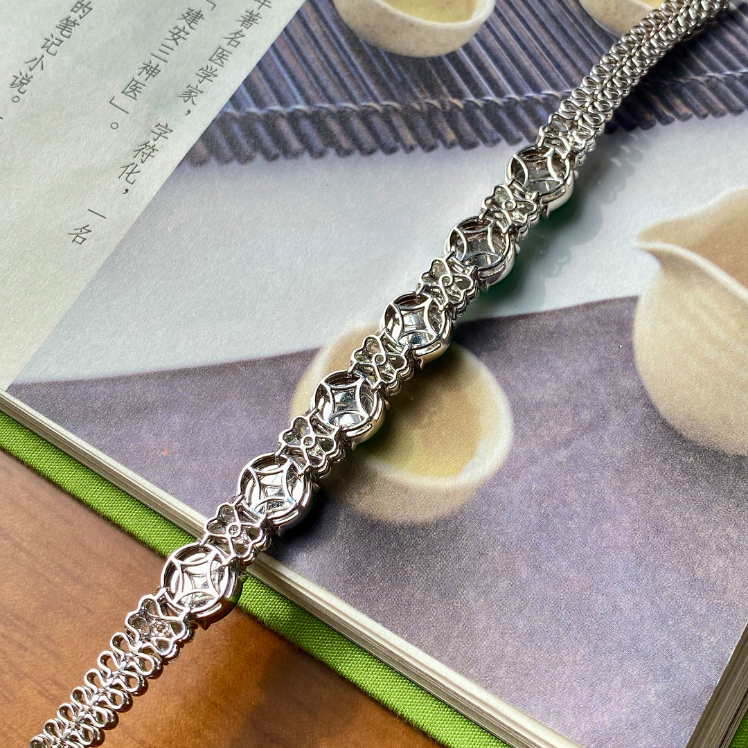Silver chain bracelet with green jadeite donut beads and clear stone accents, laid flat