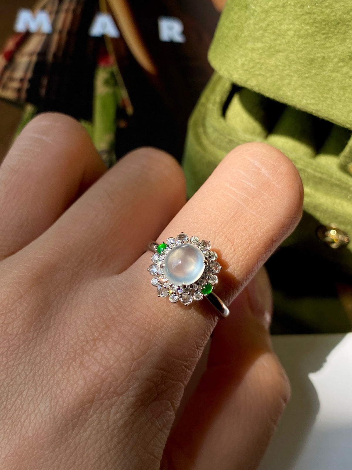 Jadeite cabochon ring on hand: round blue pearl cabochon with sparkling halo