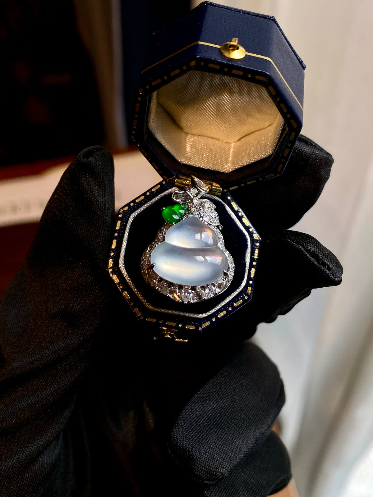 Icy white gourd pendant displayed in an open box, green gem and crystal halo