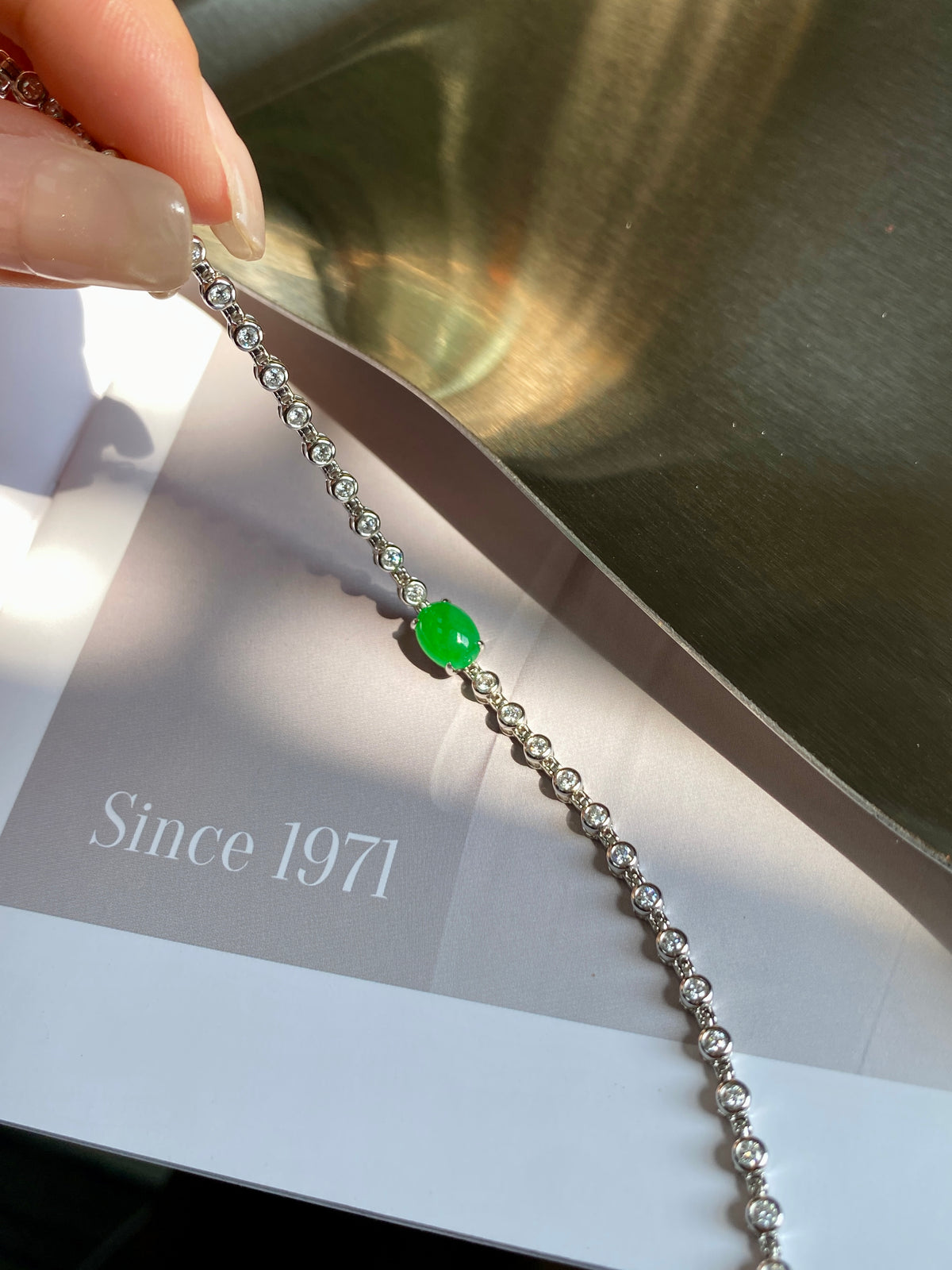 Silver-tone bracelet featuring round green jadeite cabochon and glittering bead links