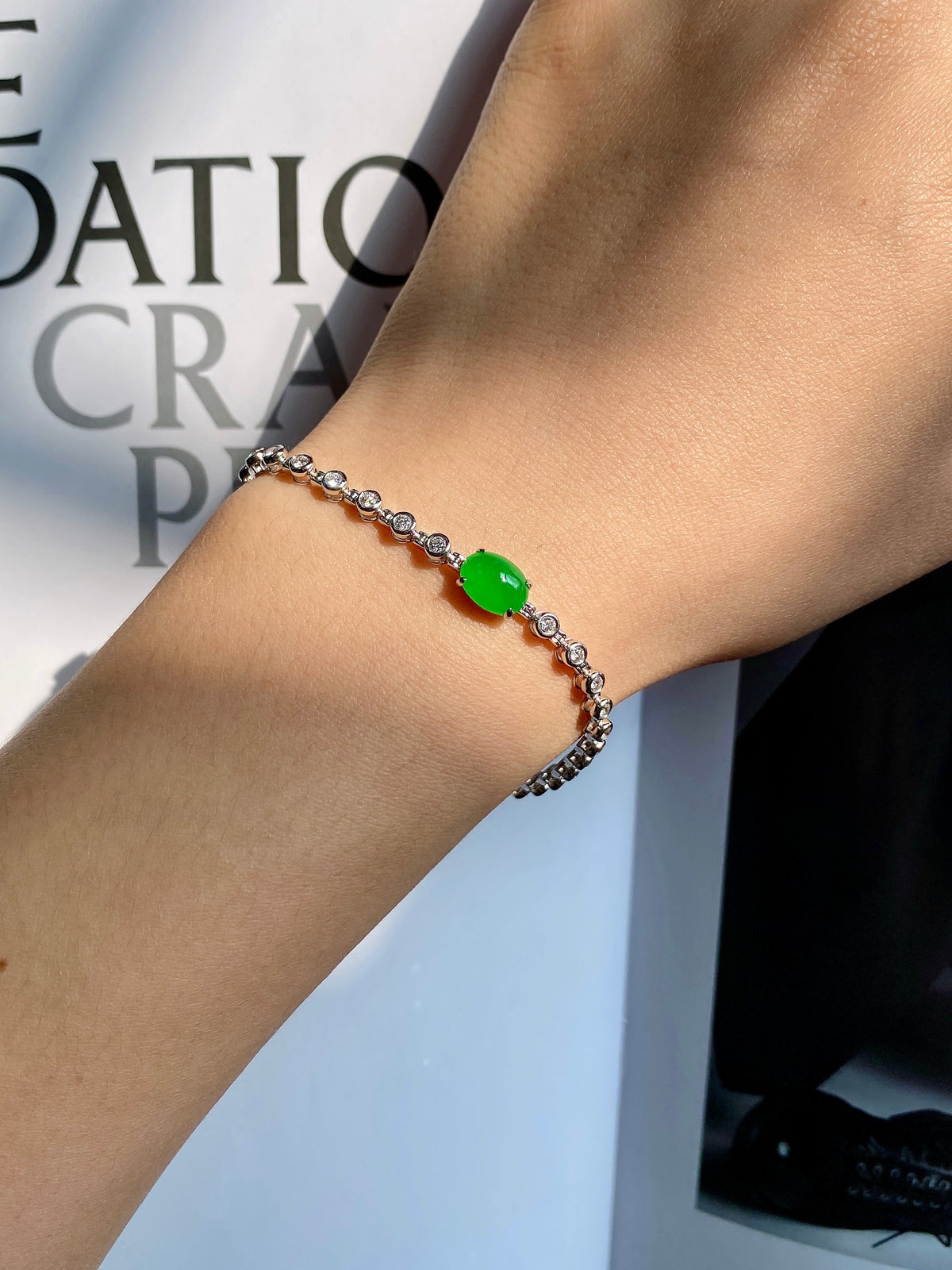 Silver-tone bracelet on wrist with round green jadeite cabochon center bead