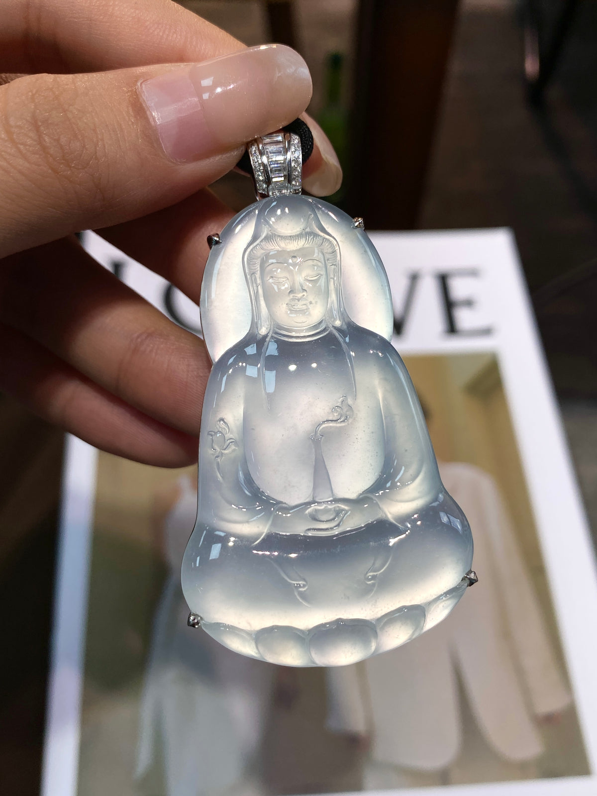 Close-up Guanyin pendant showing carved face and torso in translucent light blue-white