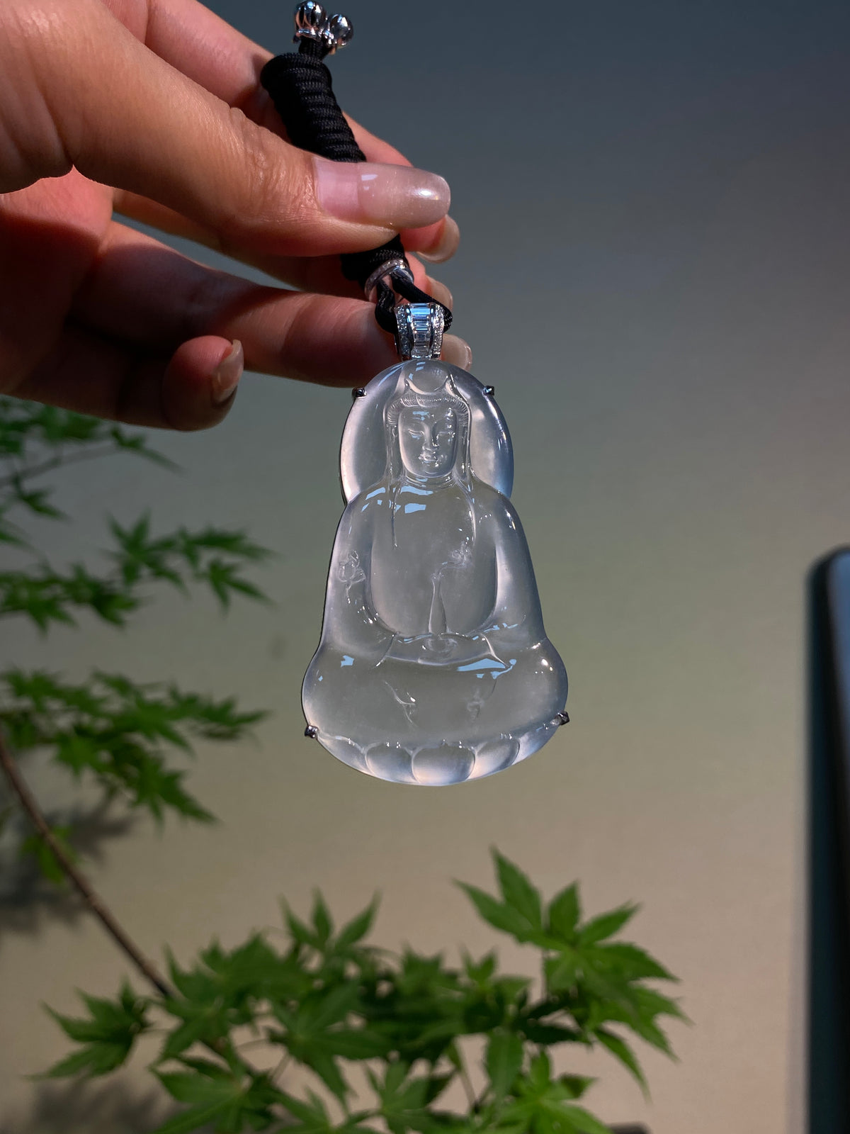 Guanyin pendant on black cord with silver-toned cap and loop bail