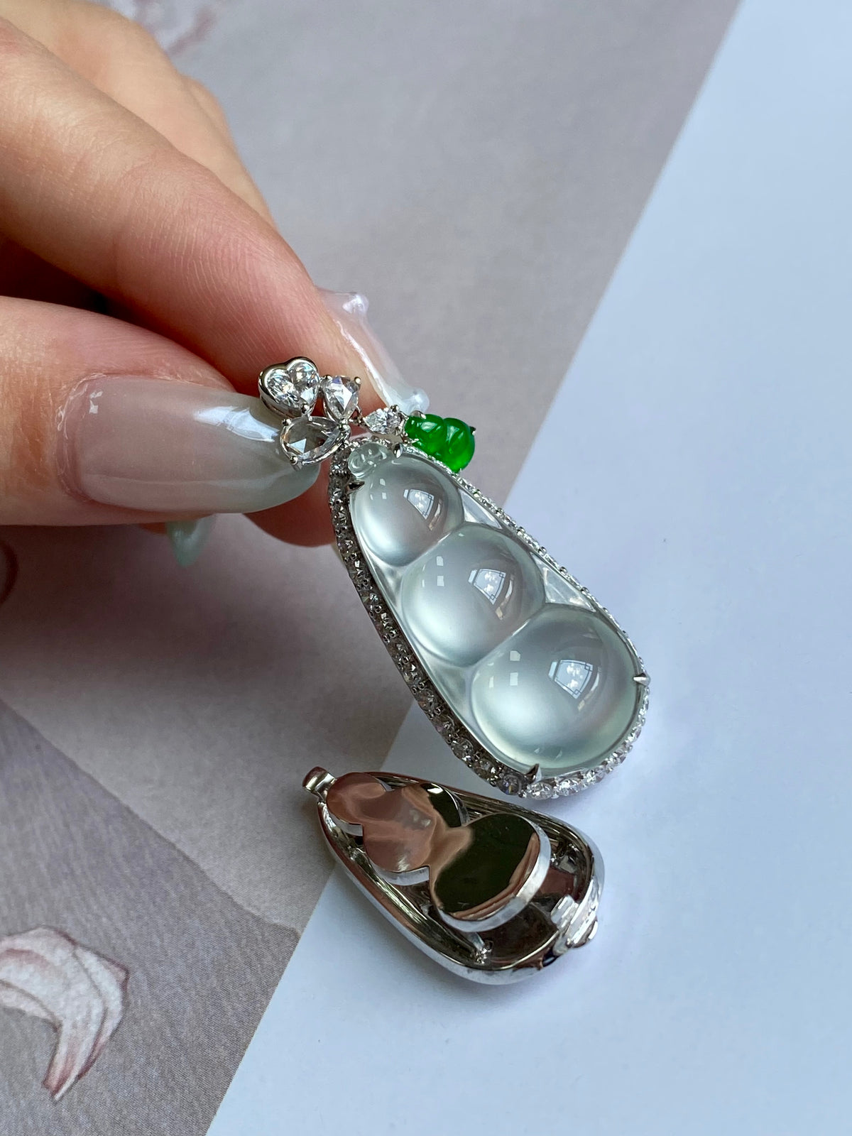 Silver-tone pea pod pendant with milky oval stones and green cabochon detail