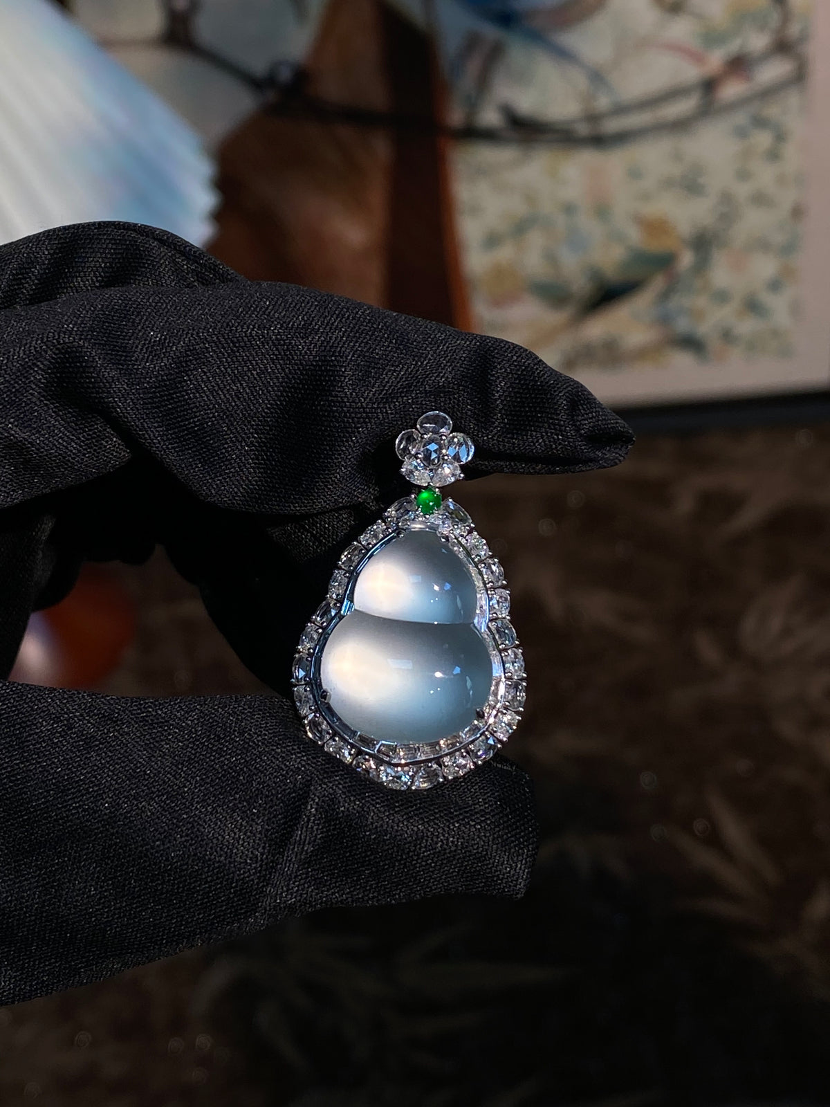 Teardrop light blue jadeite pendant with silver halo and green accent on black cloth