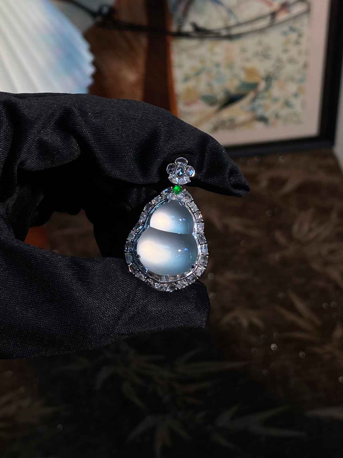 Teardrop blue jadeite pendant with round top stones and green accent on dark cloth