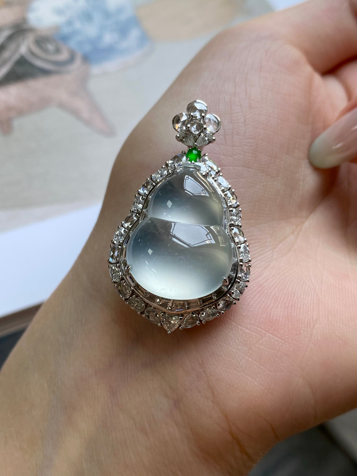 Light blue teardrop pendant with silver-toned border, clear stones, and green gem