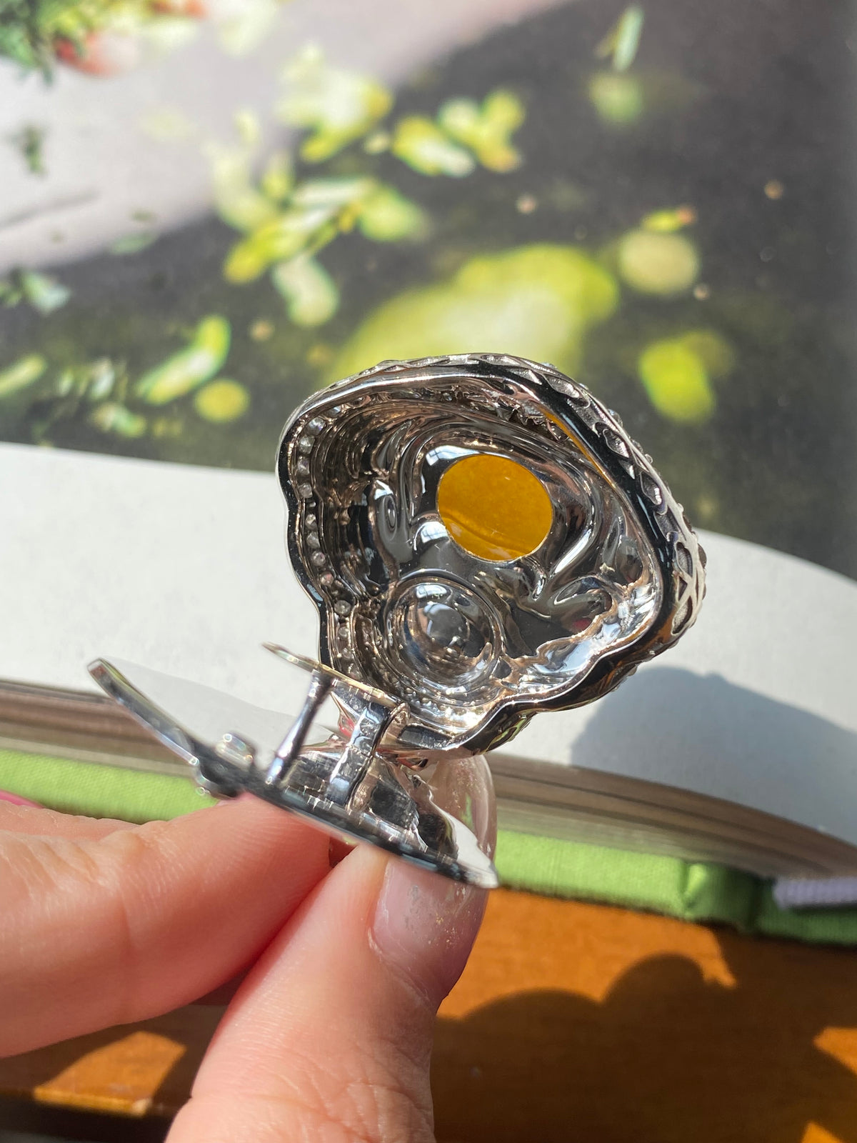 Silver bail and ridged frame holding a round yellow Laughing Buddha jadeite pendant