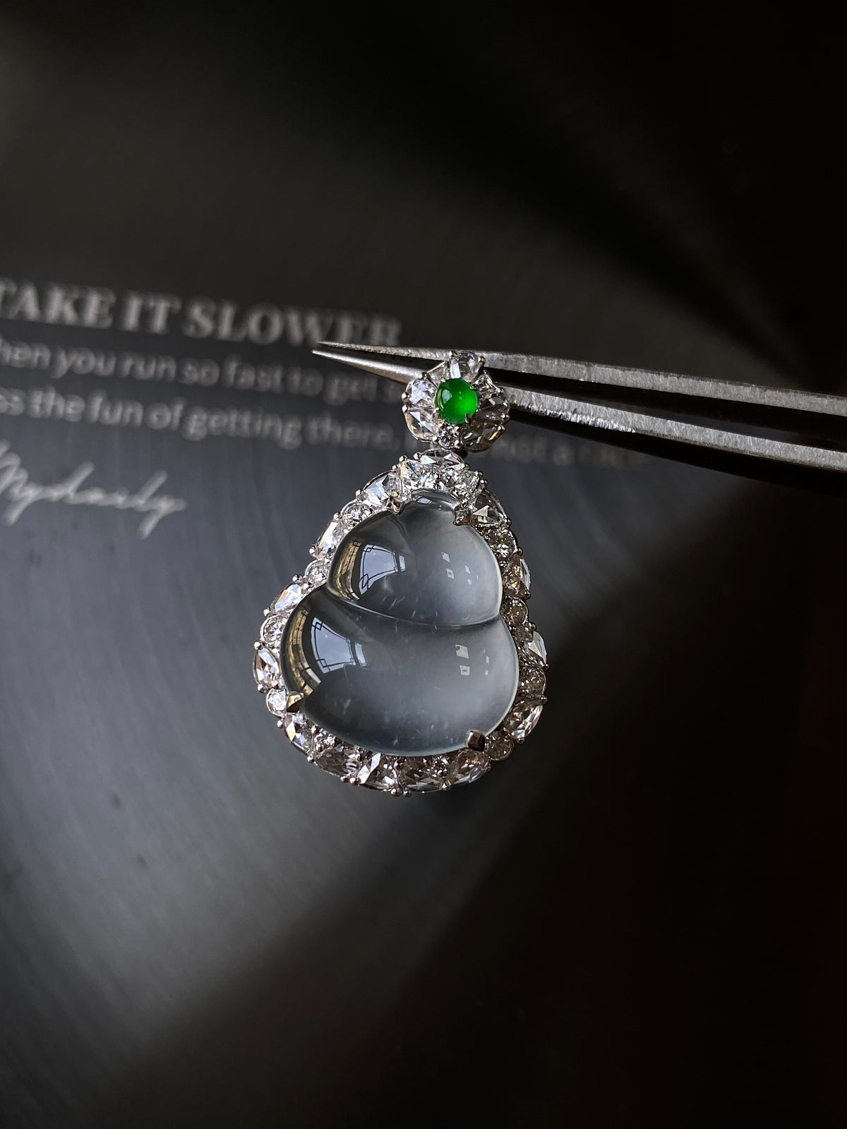 Silver-tone teardrop jade pendant with green top stone and bright halo border