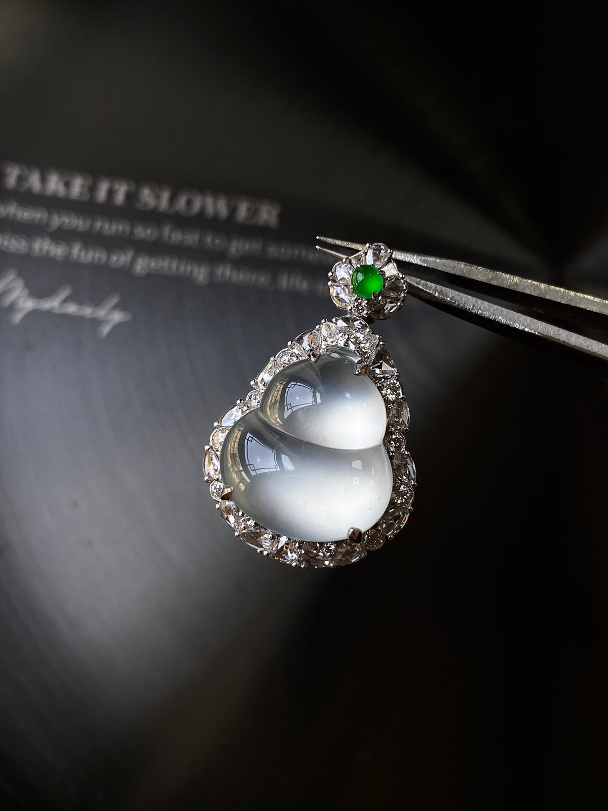 Silver-tone teardrop pendant with pale gray cabochon and green gemstone on top