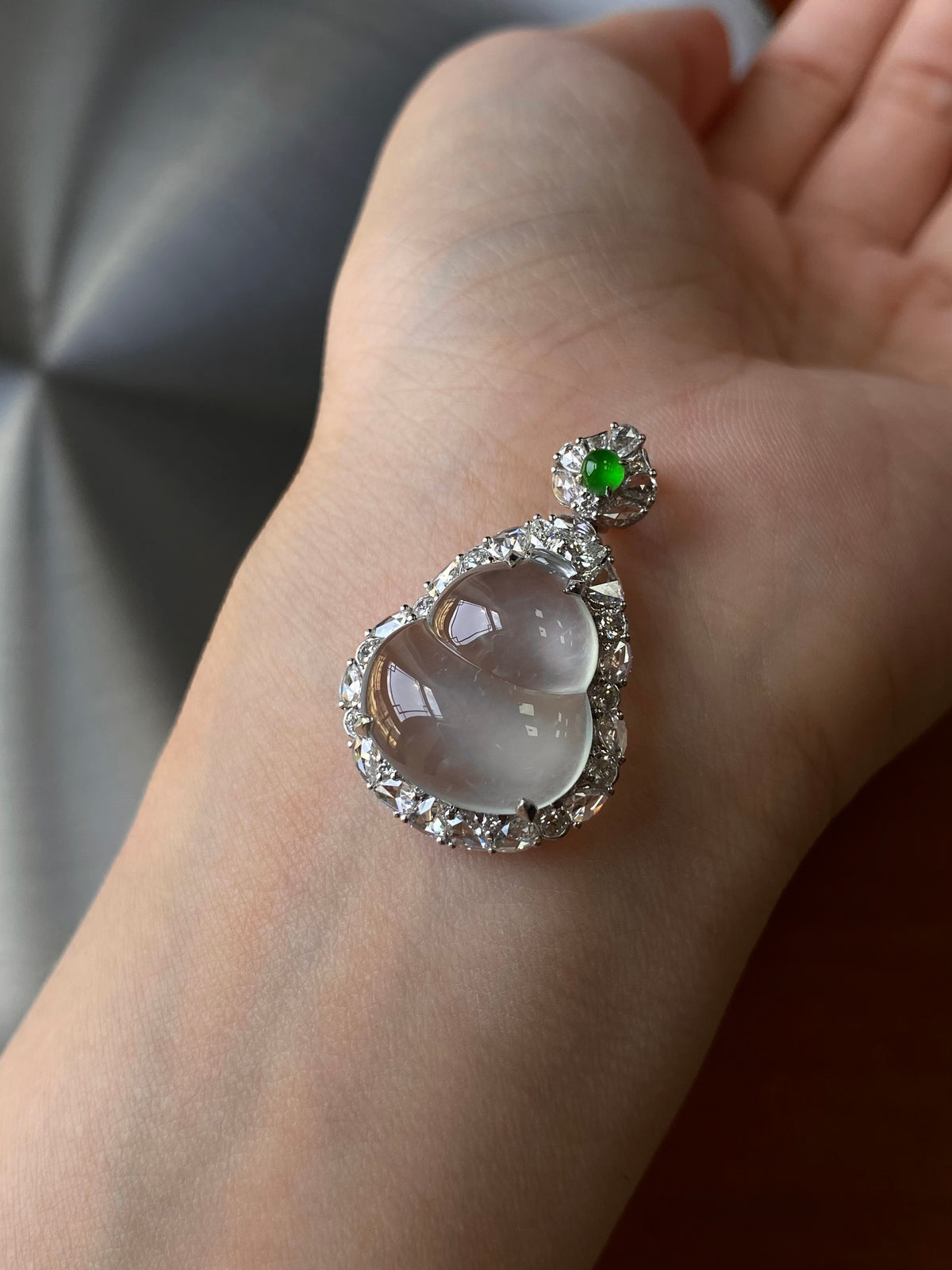Silver-tone teardrop pendant with pale gray jade cabochon, green top stone, halo