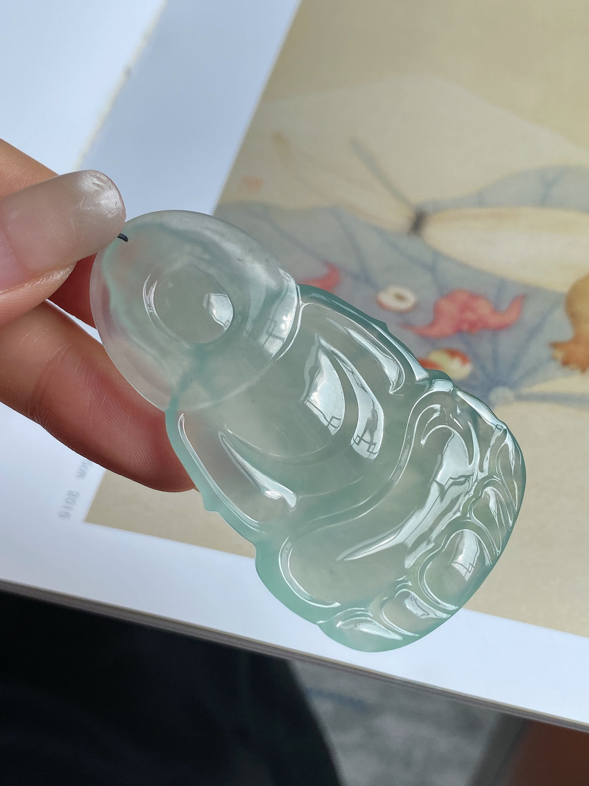 Light green jadeite Guanyin pendant, side view in hand with black cord