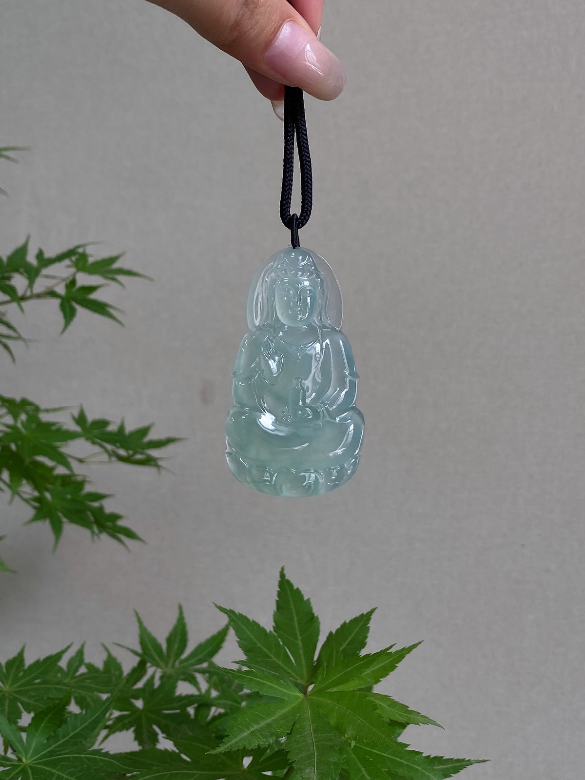 Light green jadeite Guanyin pendant with black cord, front view