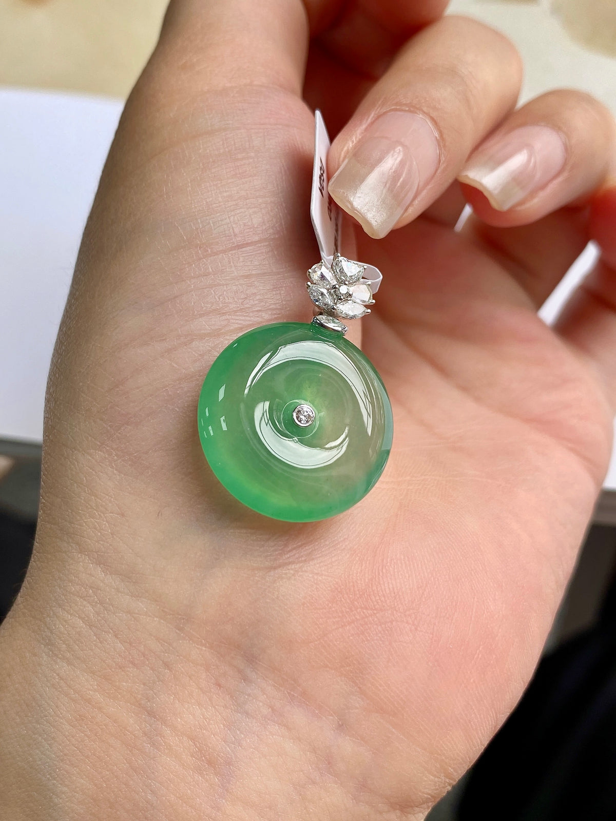 Light green jadeite donut pendant on a silver bail with round clear stone top