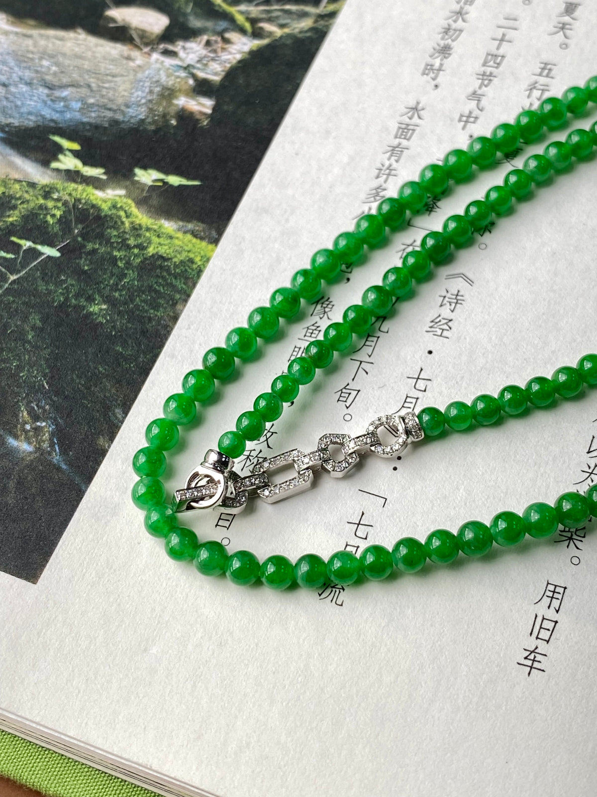Vibrant green jadeite beaded necklace with silver clasp and linked charm.