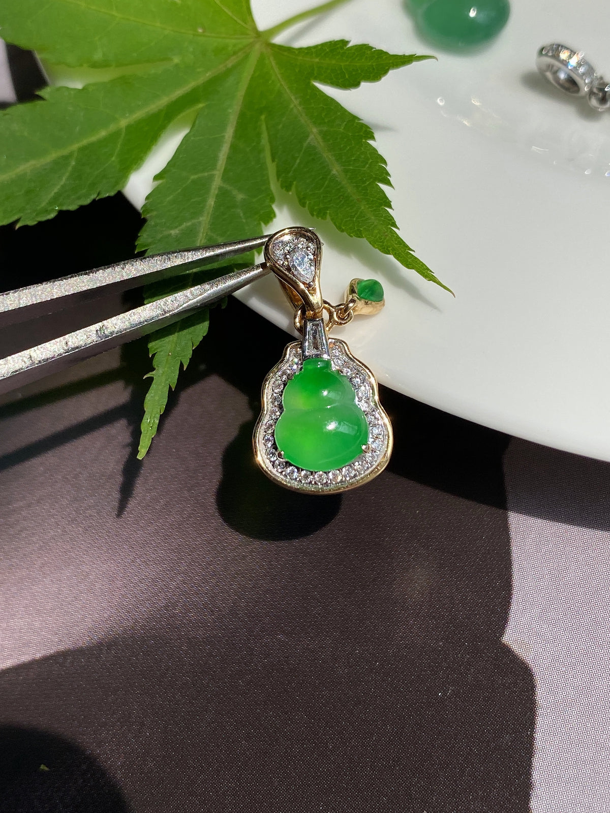 Gold-tone jadeite gourd pendant with bright green teardrop center and jeweled border