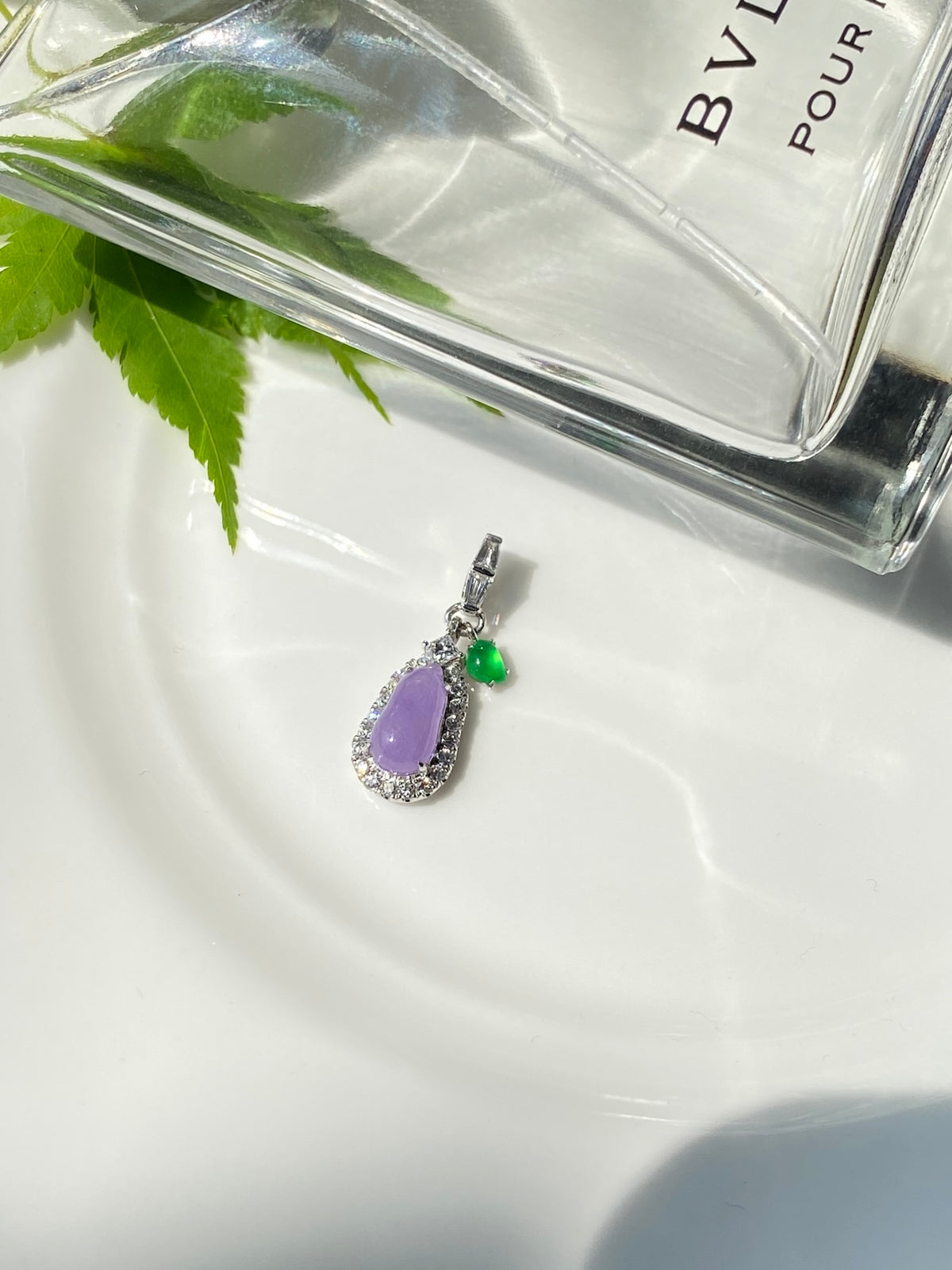 Lavender oval pendant with silver prong setting and green bead charm, dangling
