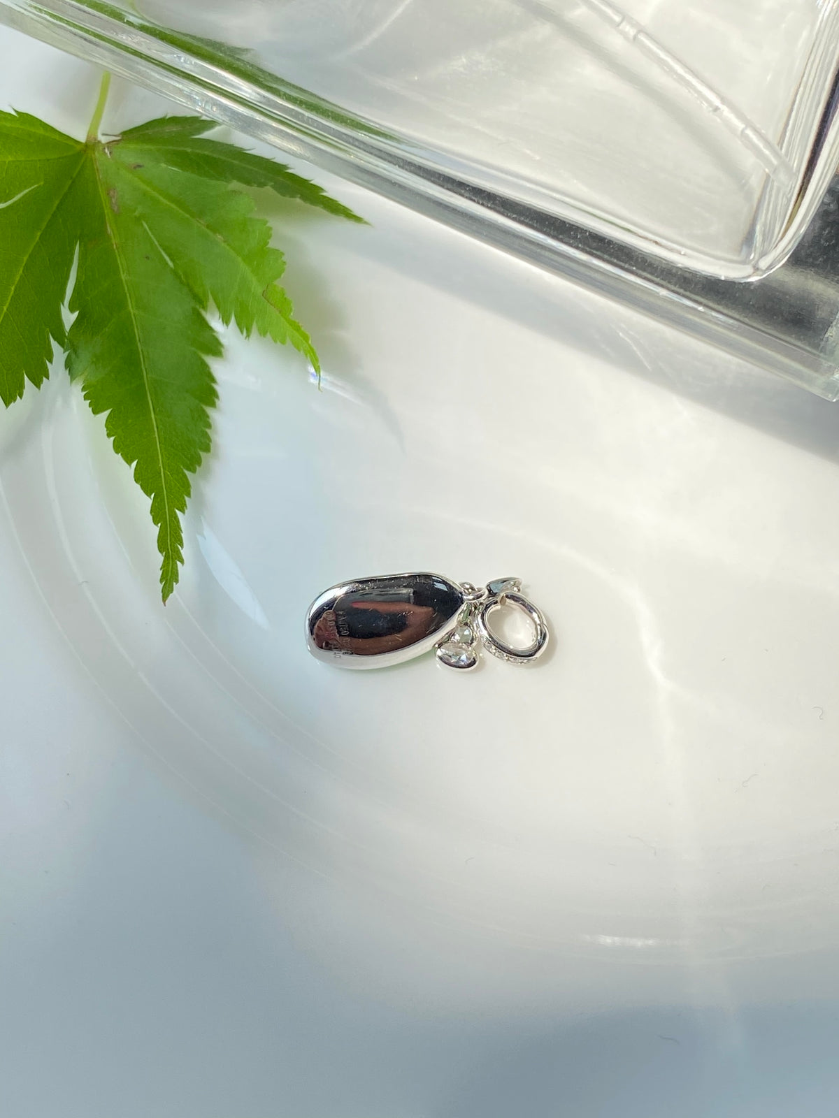 Dark-backed green jadeite bean pendant with silver bail and clasp loop