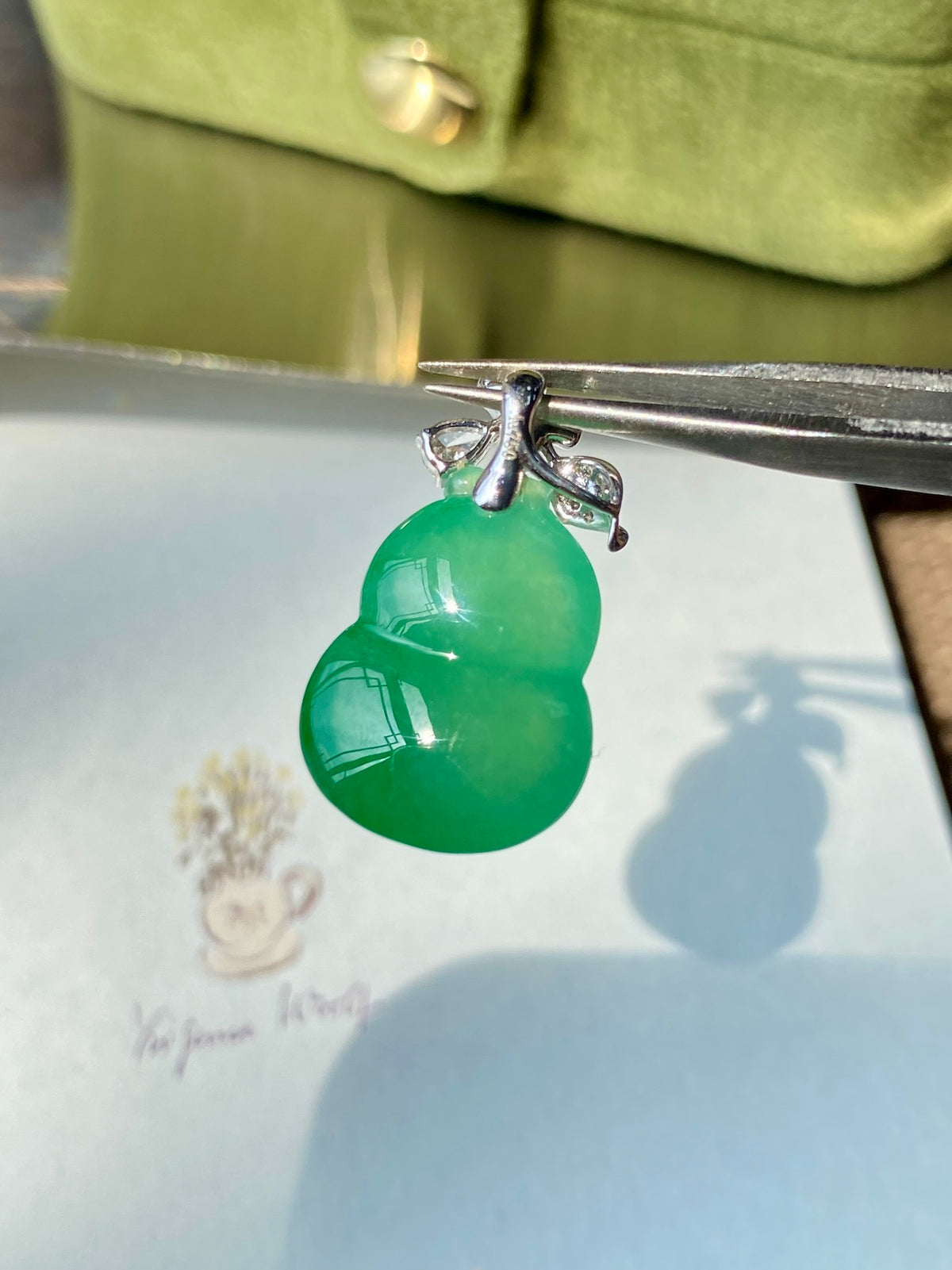 Green jadeite gourd pendant close-up with silver-tone bail and clear stones