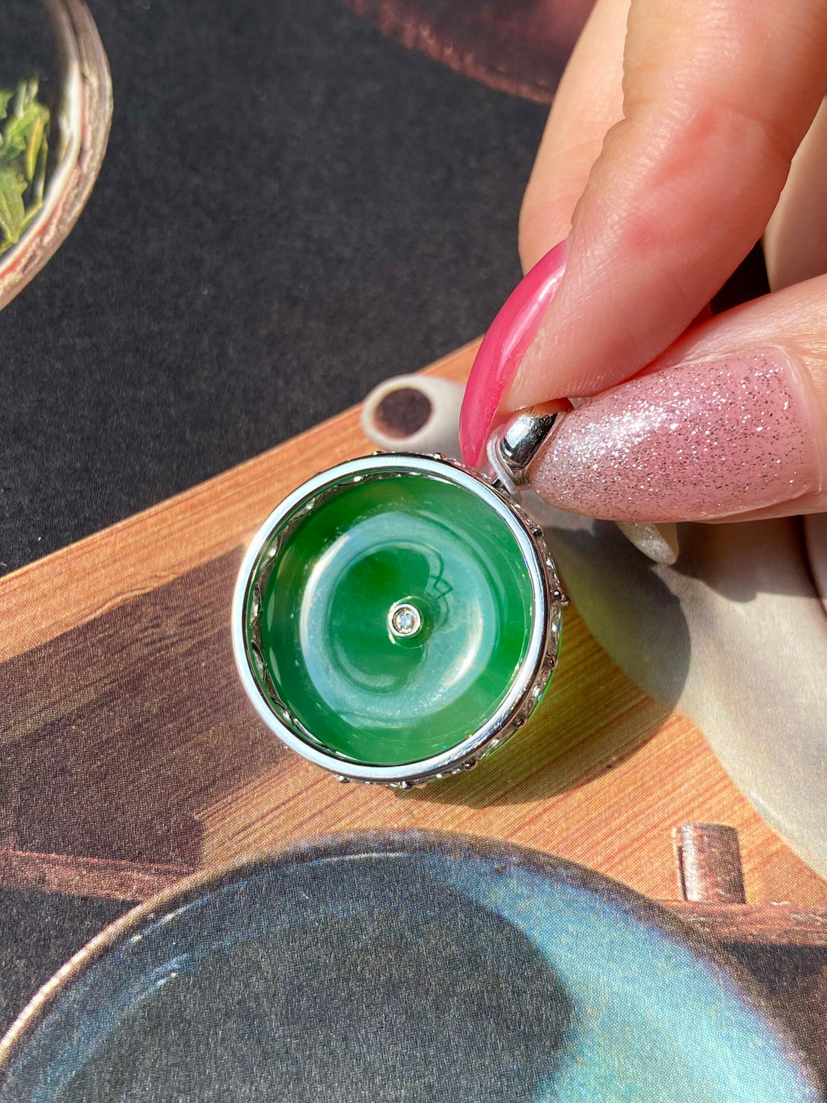 Green jadeite donut pendant with silver prong rim and central small round gem