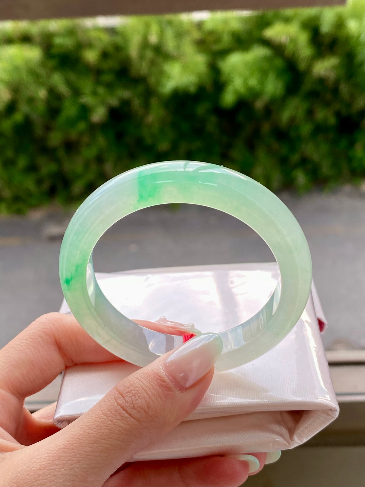 Pale green translucent jadeite bangle with shiny surface, round opening in focus