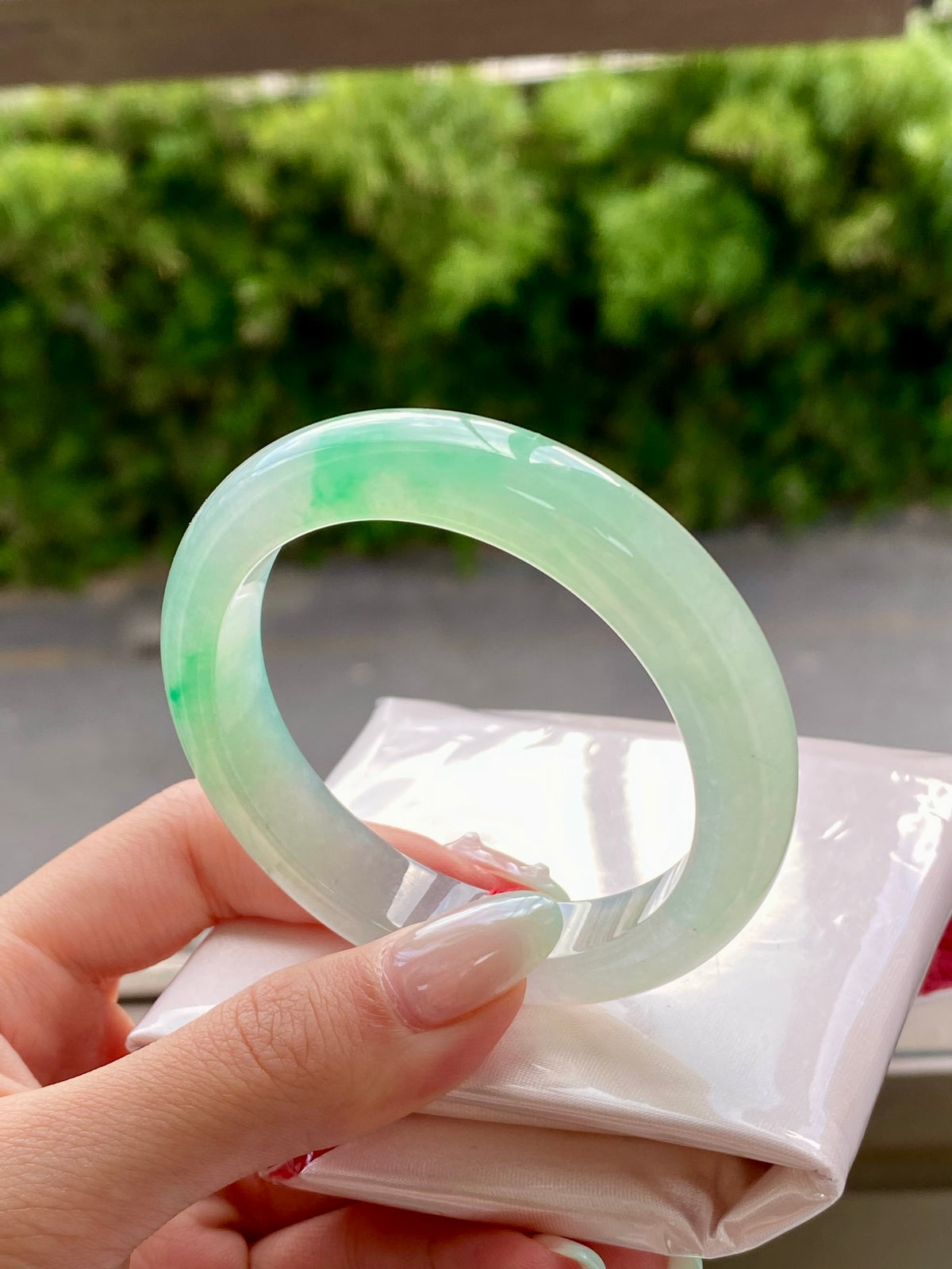 Translucent pale green jadeite bangle, angled view showing full circular shape