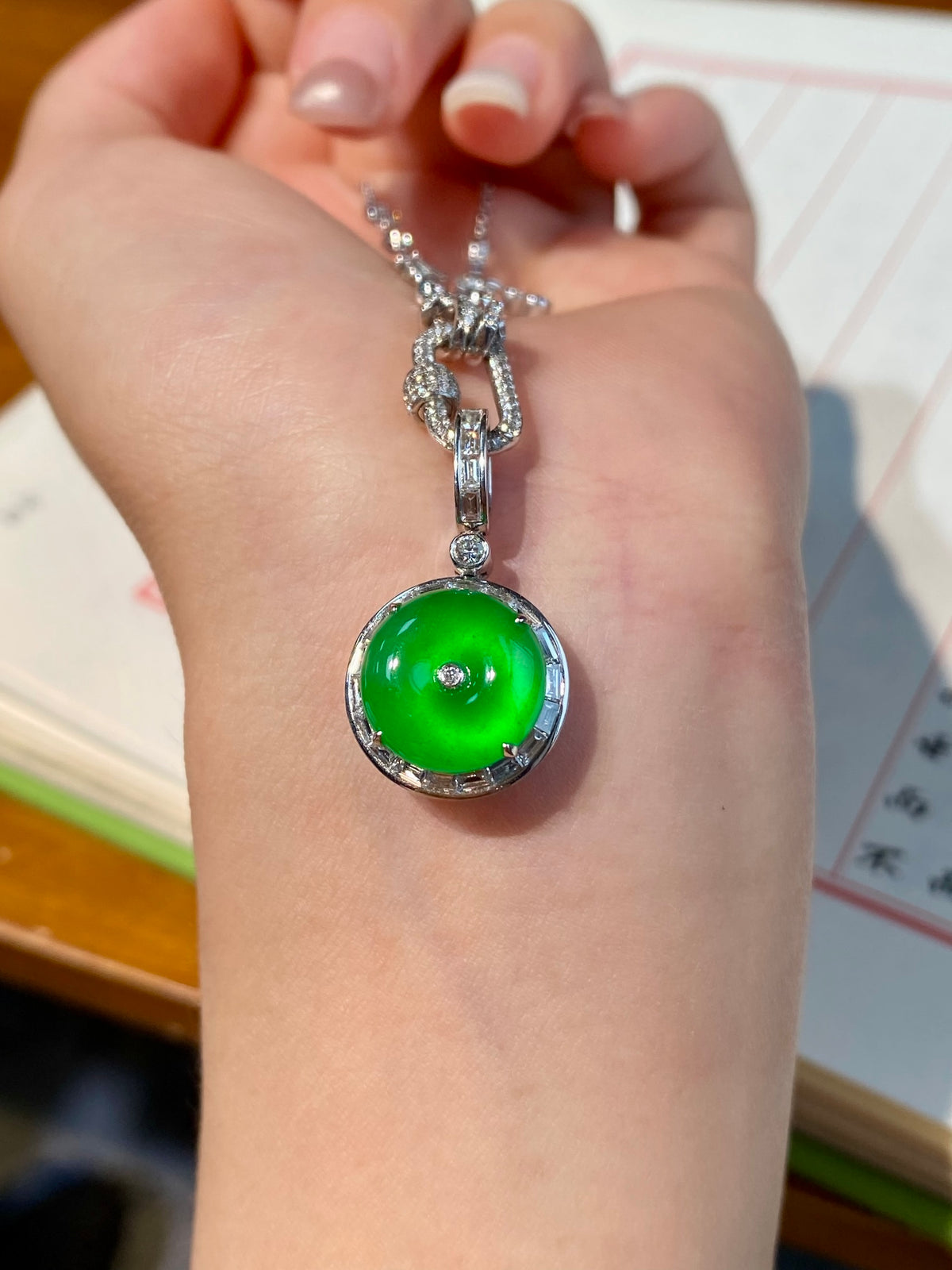 Green jadeite donut pendant silver necklace worn on hand, chain links