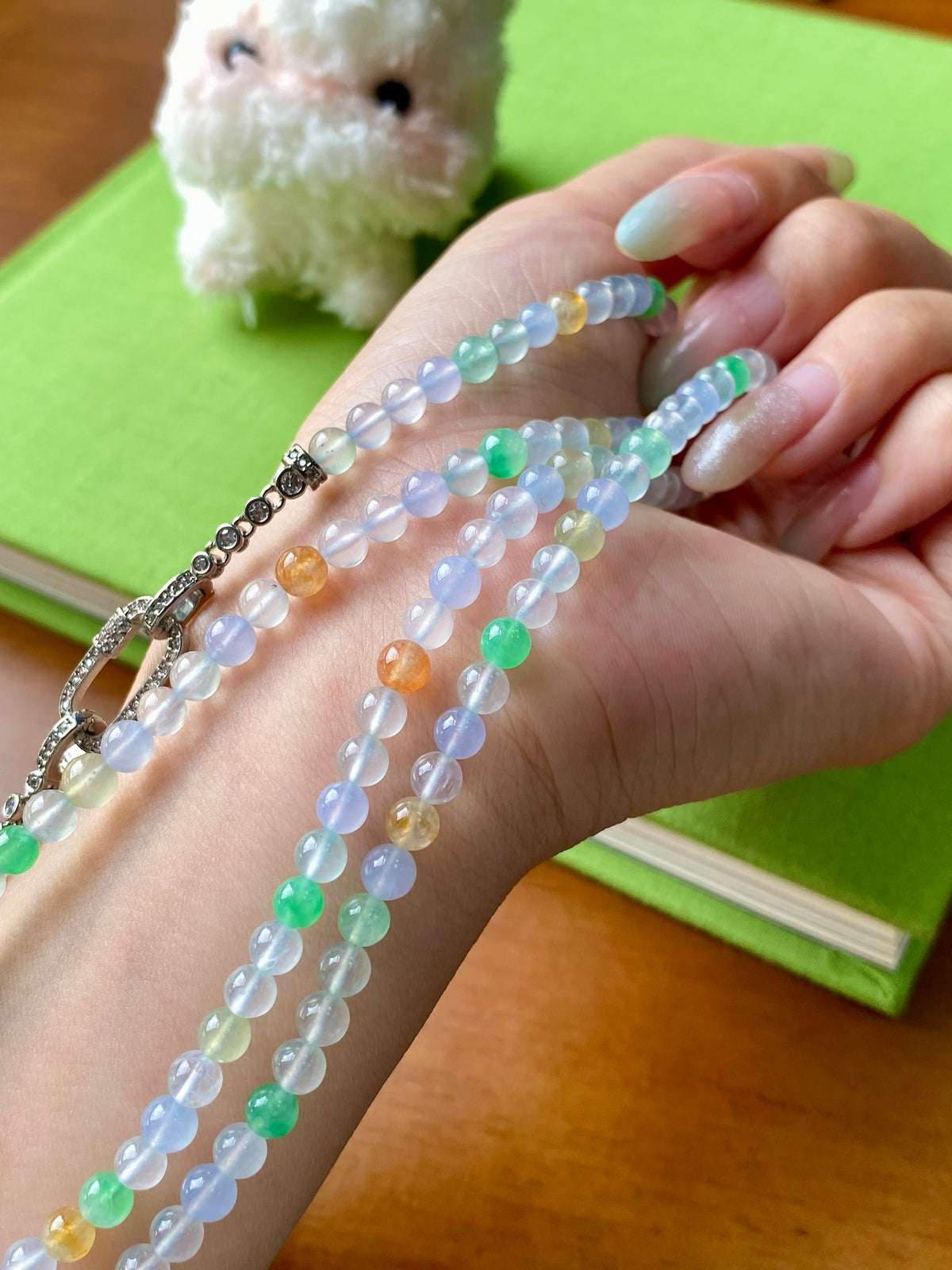 Multi-strand beaded necklace close-up with light blue, green, orange beads and metal clasp