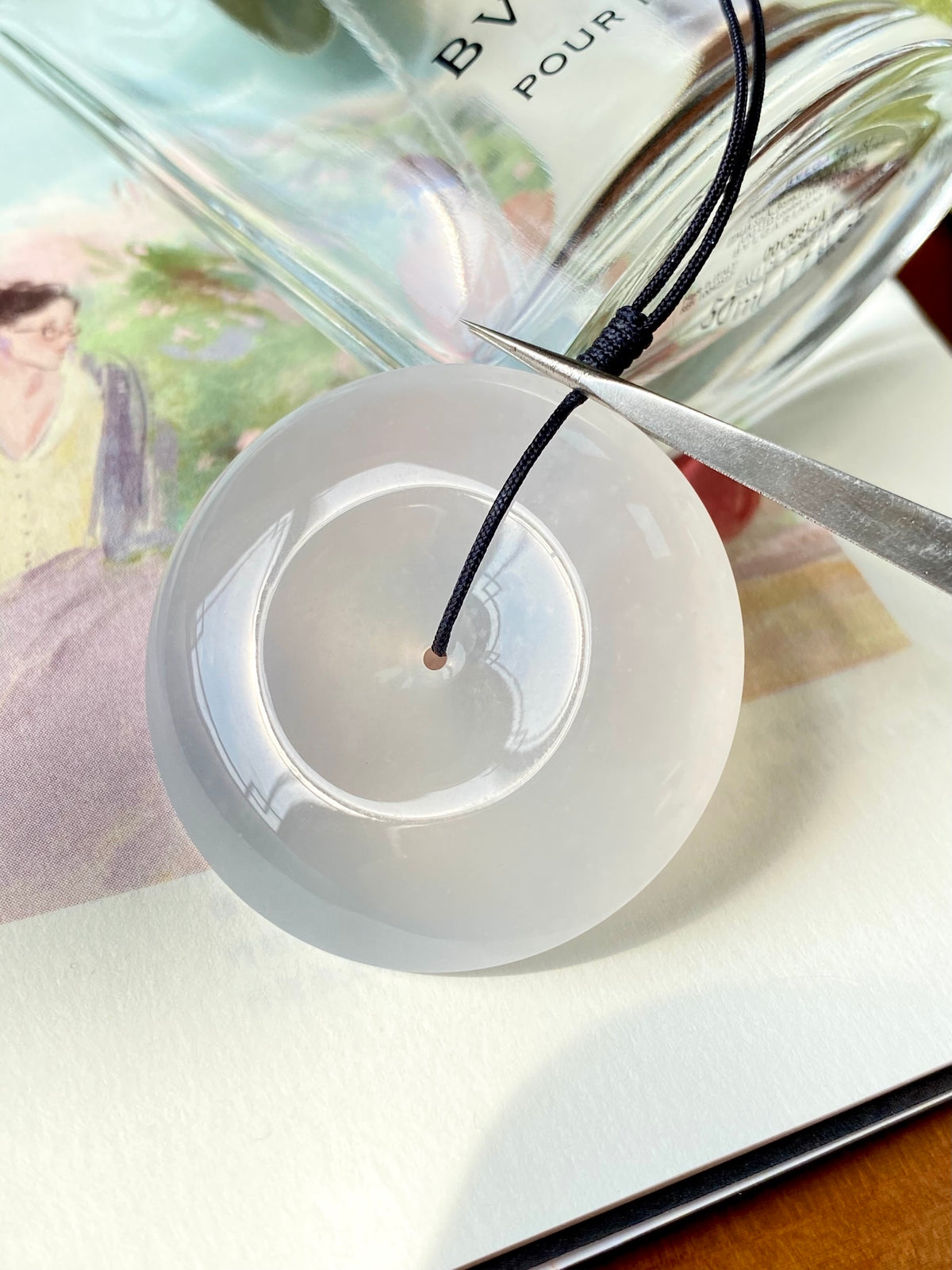 Icy white jadeite donut with black cord and visible inner hollow